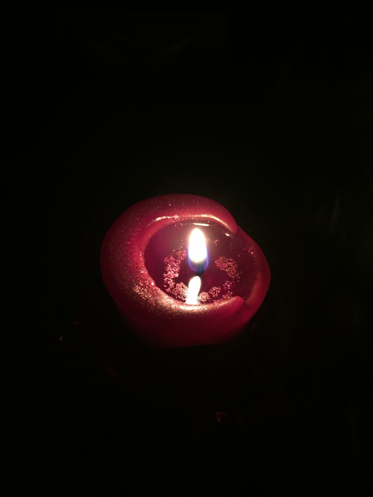 A red lit candle in darkness
